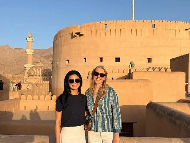 Two women posing in front of round tower at Nizwa Fort