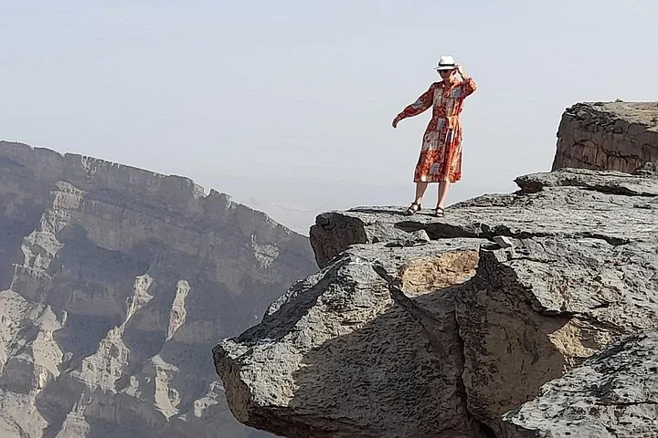Frau im Kleid steht am Klippenrand und blickt auf eine Schlucht