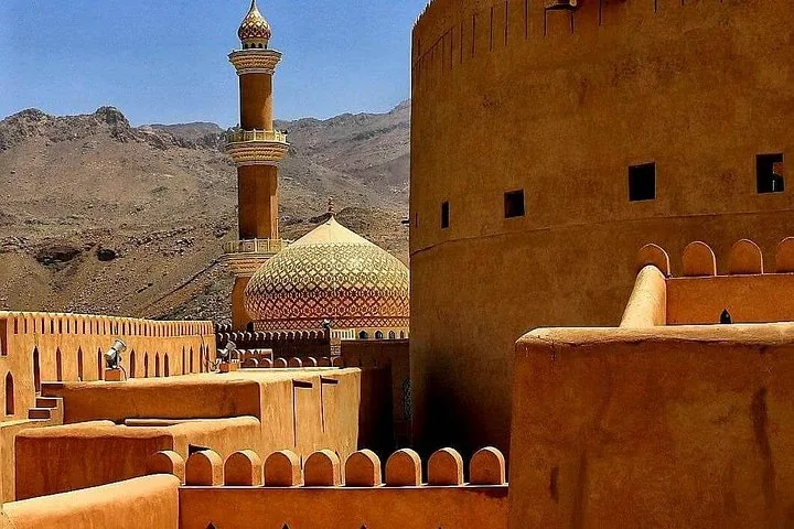 Festung Nizwa mit traditioneller Architektur und Moschee-Minarett im Hintergrund
