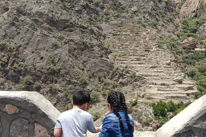 Zwei Personen betrachten von einem Aussichtspunkt aus die terrassierte Berglandschaft